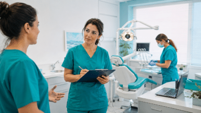 Coordinatrice di una clinica odontoiatrica ascolta una collega mentre vigila sulle procedure di sicurezza.